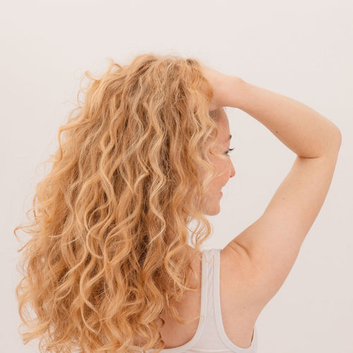 Boucles blondes dorées, main dans les cheveux, après avoir formé la boucle